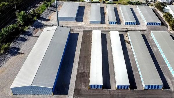 Boxes and a wrapped item on a blue cart in a storage unit hallway lined with red doors.