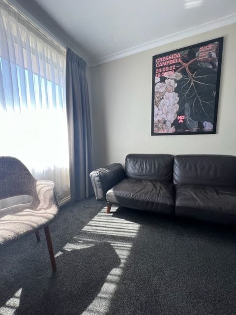 Living room with sofa, chair, window with curtains, and artwork on the wall.