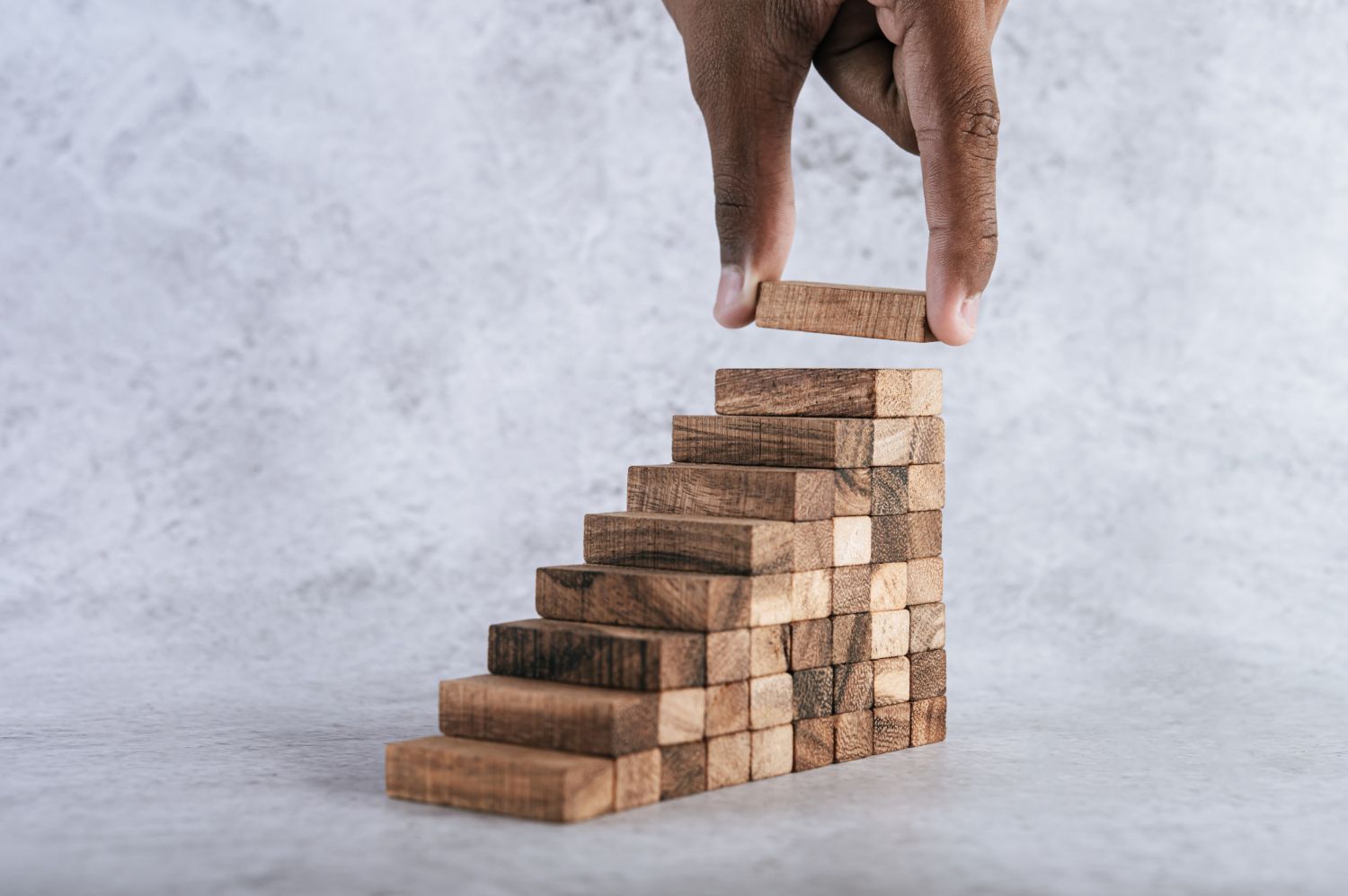 A person is building a staircase out of wooden blocks.