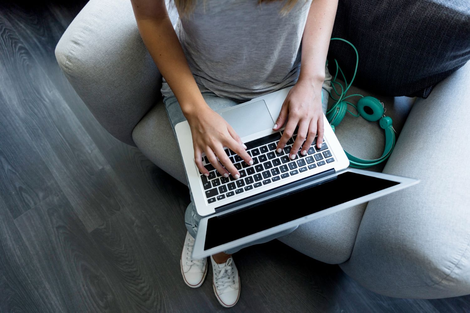 A woman is sitting on a couch using a laptop computer.