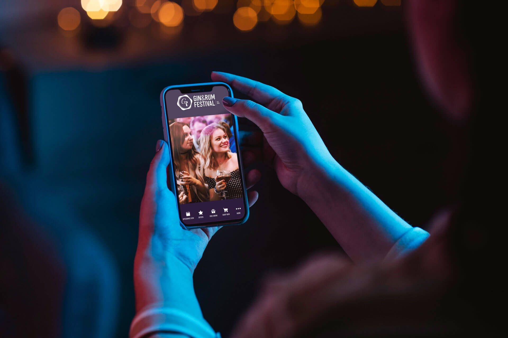 A person is taking a picture of two women on a cell phone.