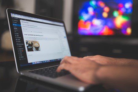 A person is typing on a laptop computer with a picture of a cup of coffee on the screen.