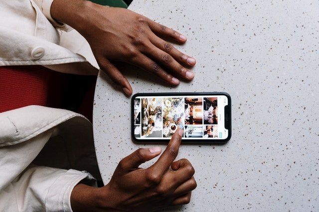 A person is sitting at a table using a cell phone.