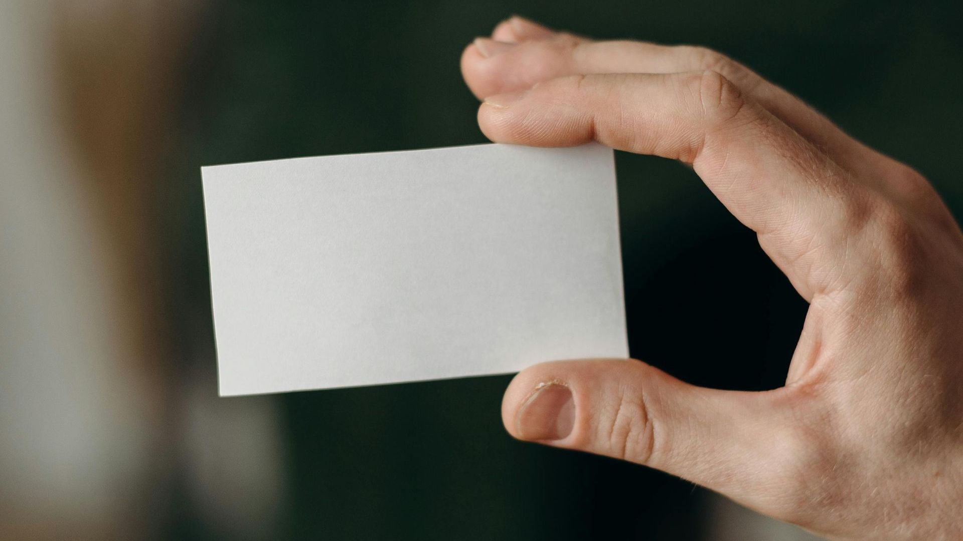 A person is holding a white business card in their hand.