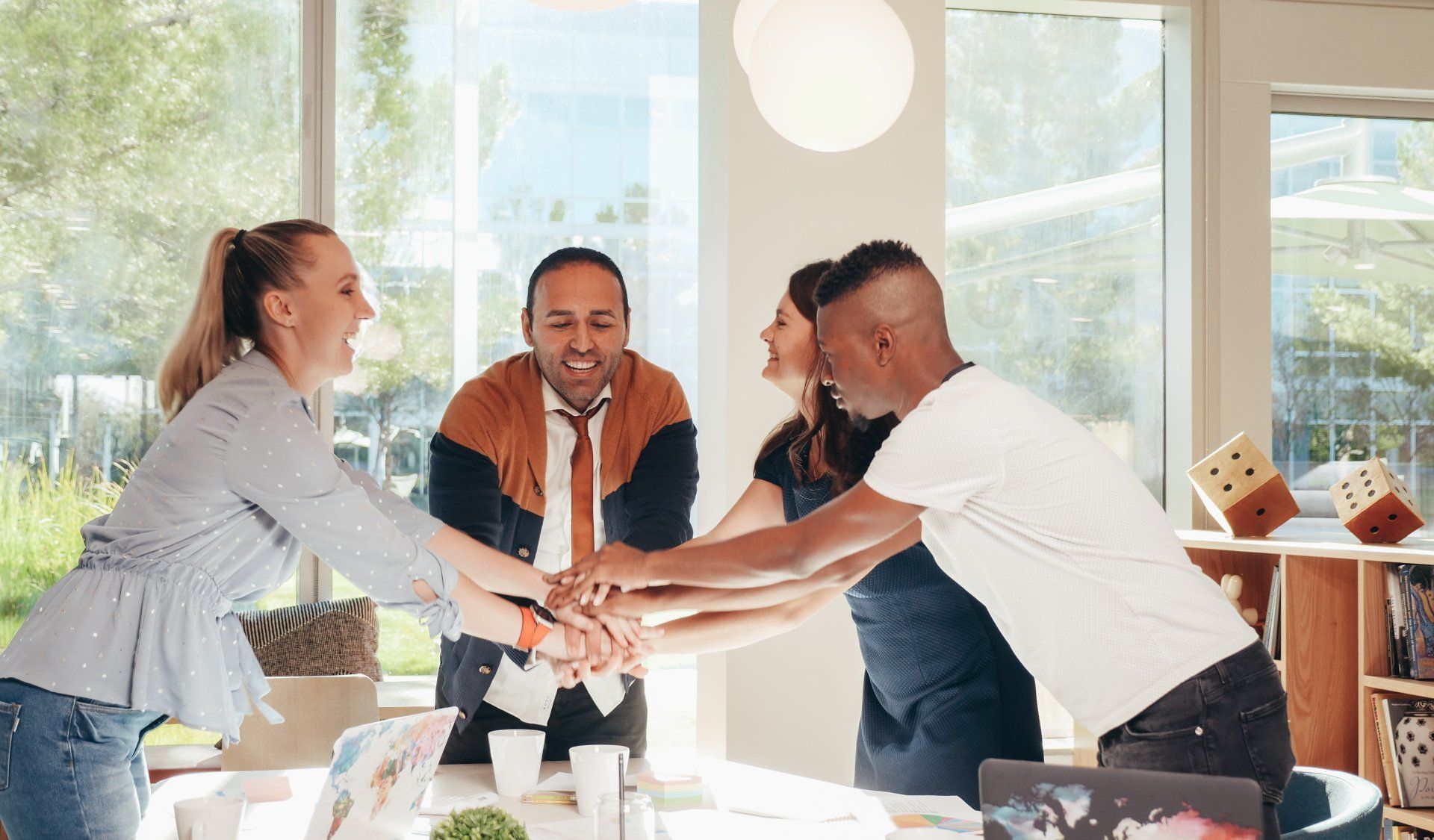 A group of people are putting their hands together in an office.