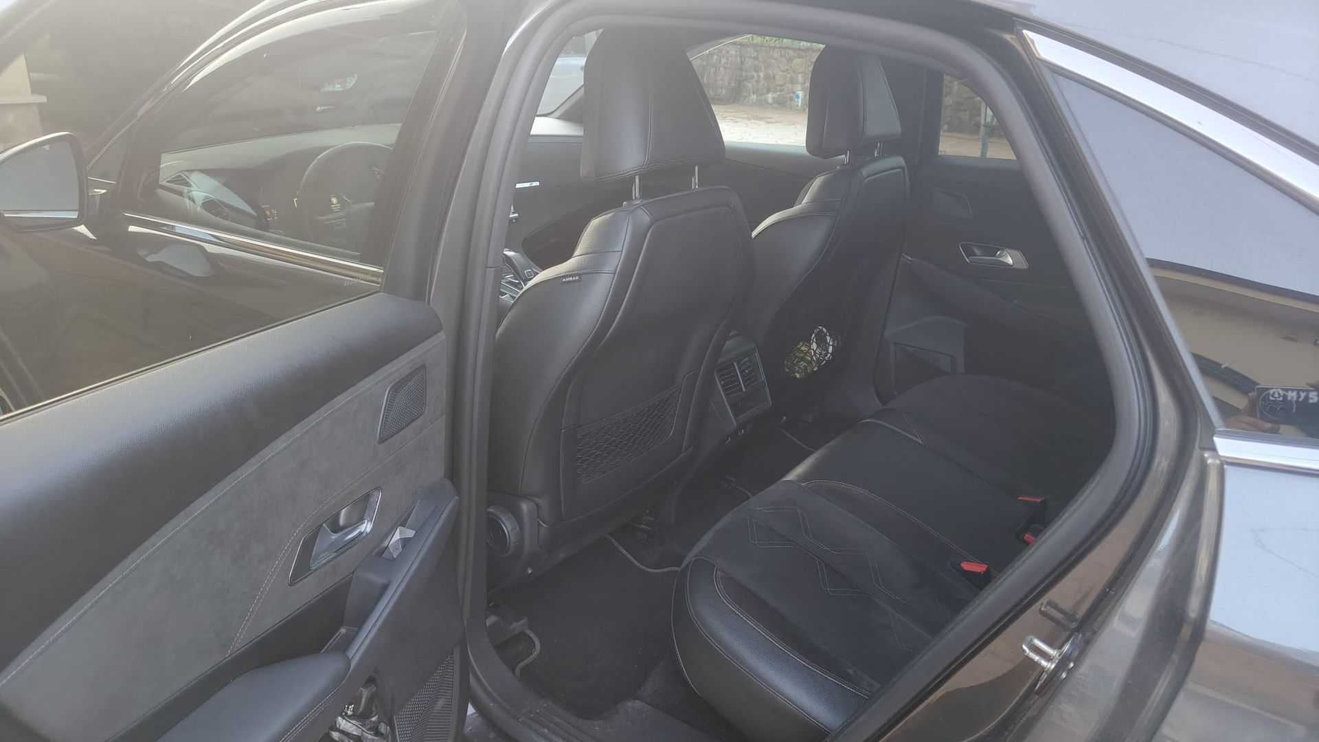 Cruscotto di una Fiat 500L, interni neri con volante, schermo dell'infotainment e cambio visibili.