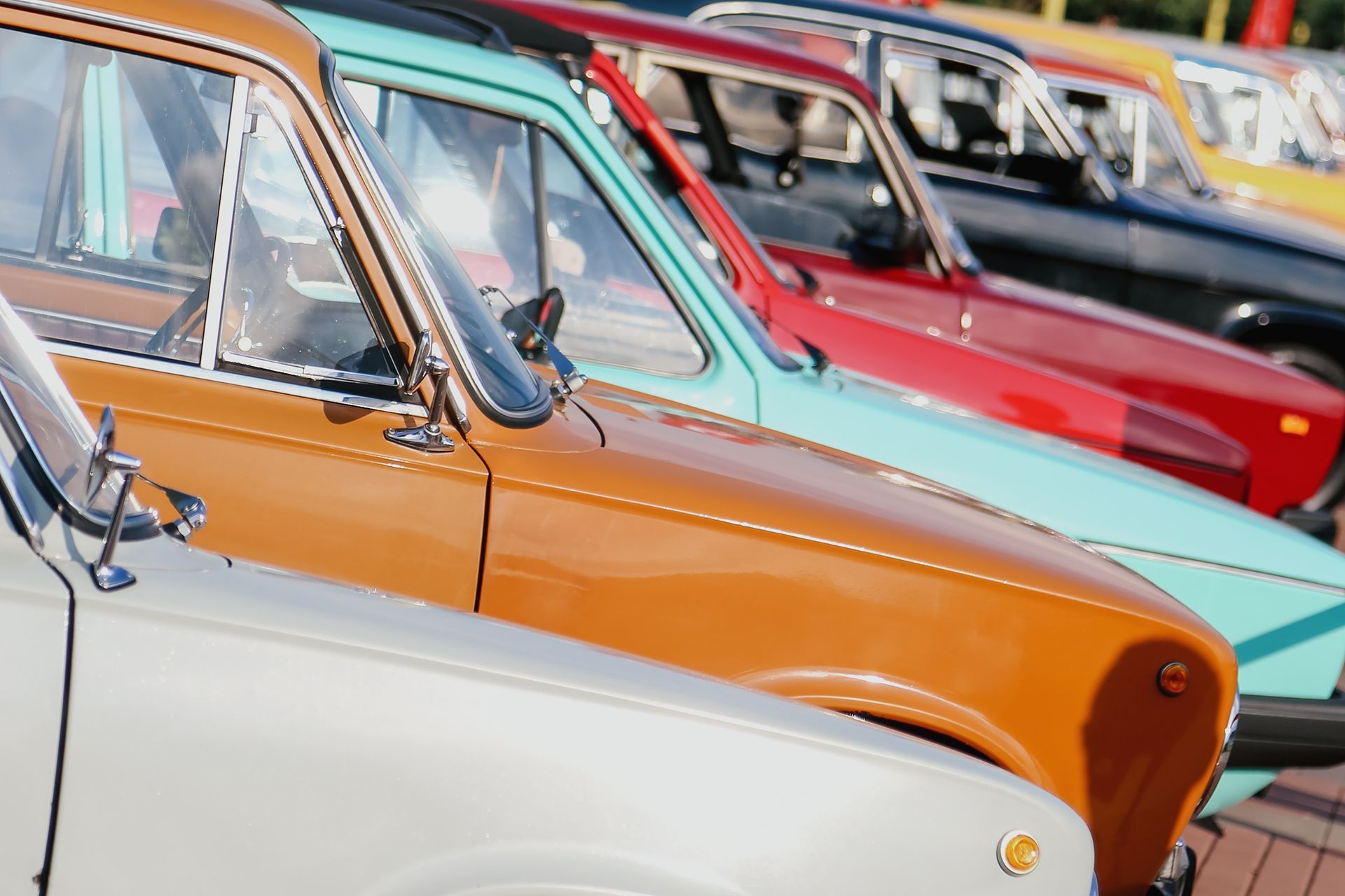 Row of colorful classic cars parked outdoors.