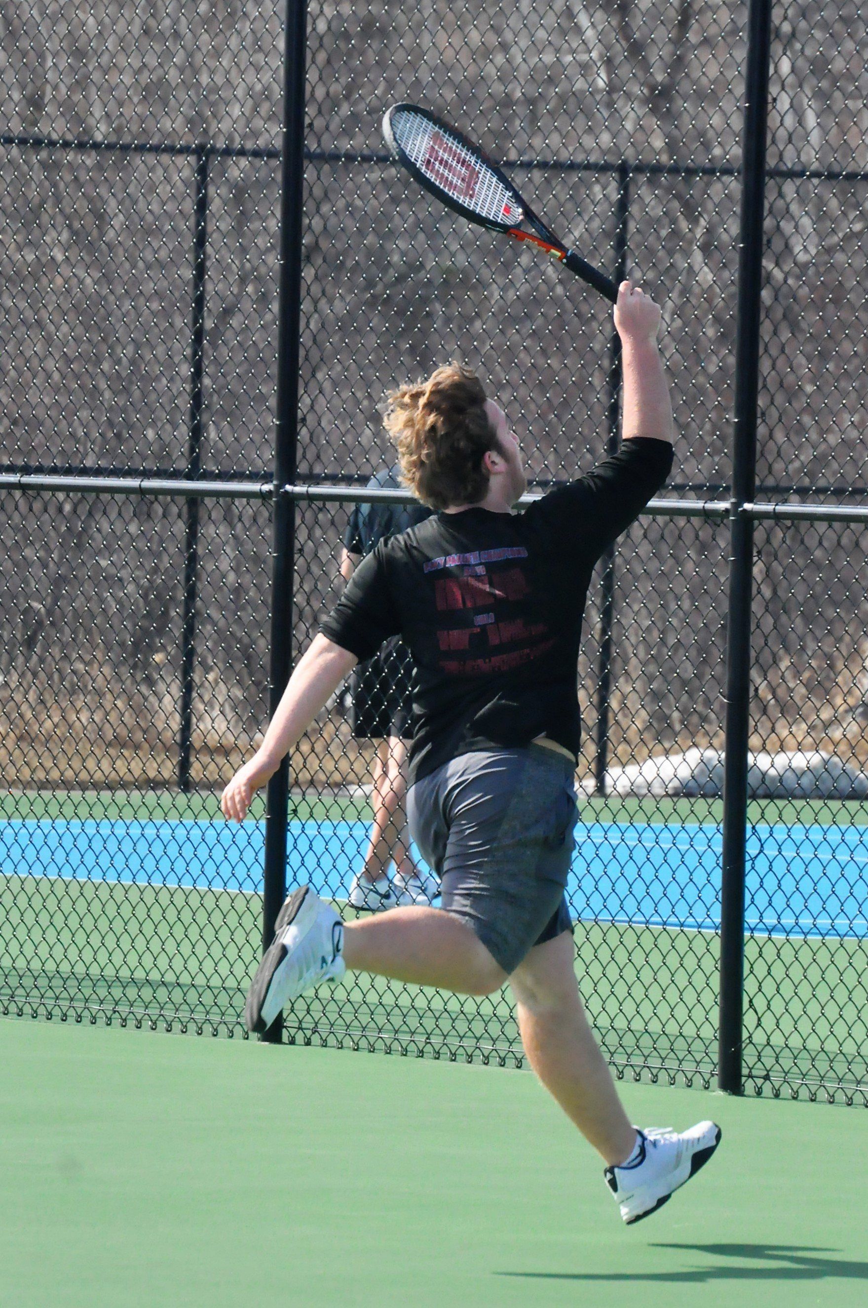 Superior Spartan boy's tennis player chasing down a shot