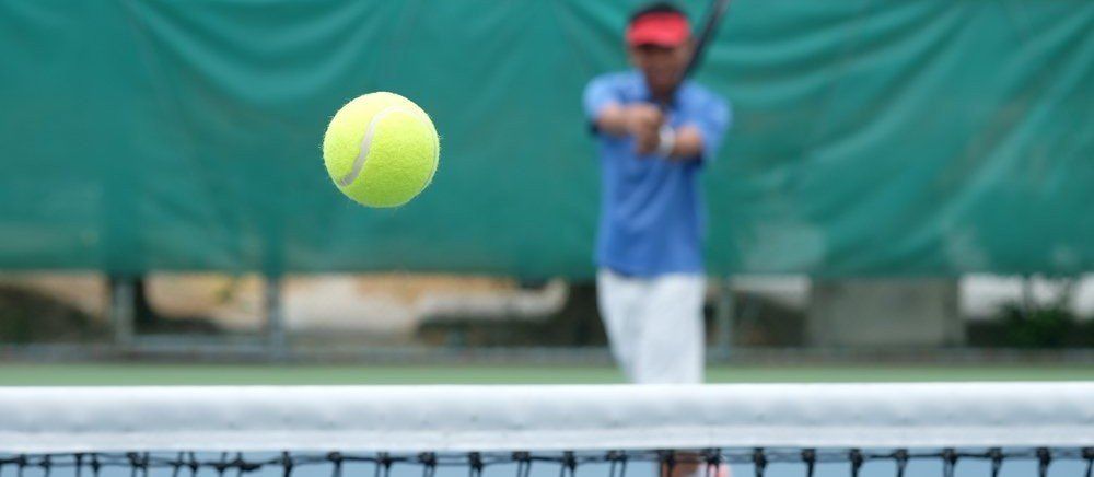 blurry tennis player hitting a ball at the camera