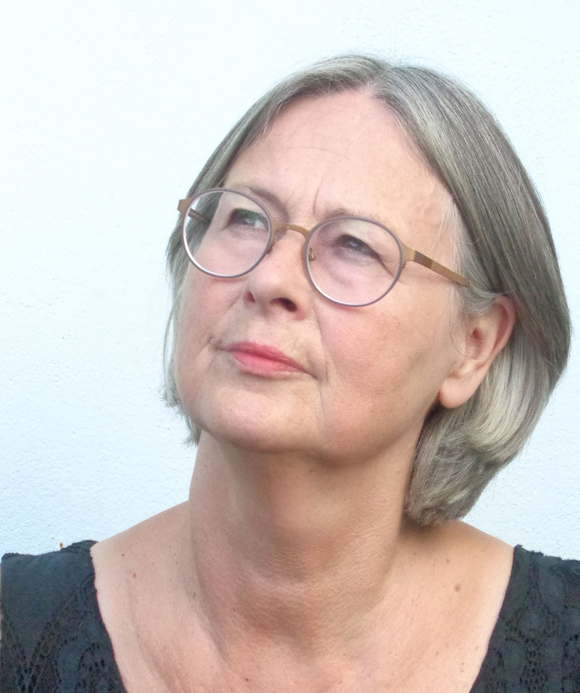 Eine Frau mit Brille und schwarzem Hemd schaut nach oben.