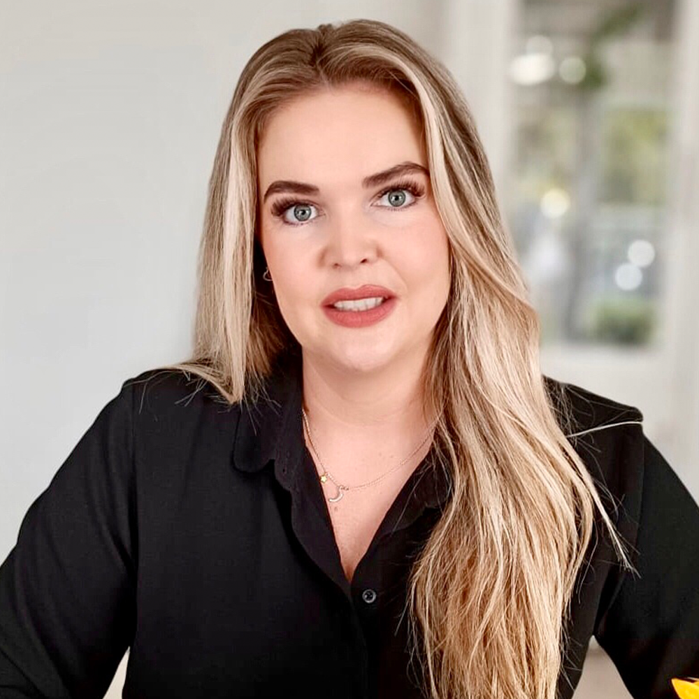 Eine Frau mit langen blonden Haaren trägt ein schwarzes Hemd.