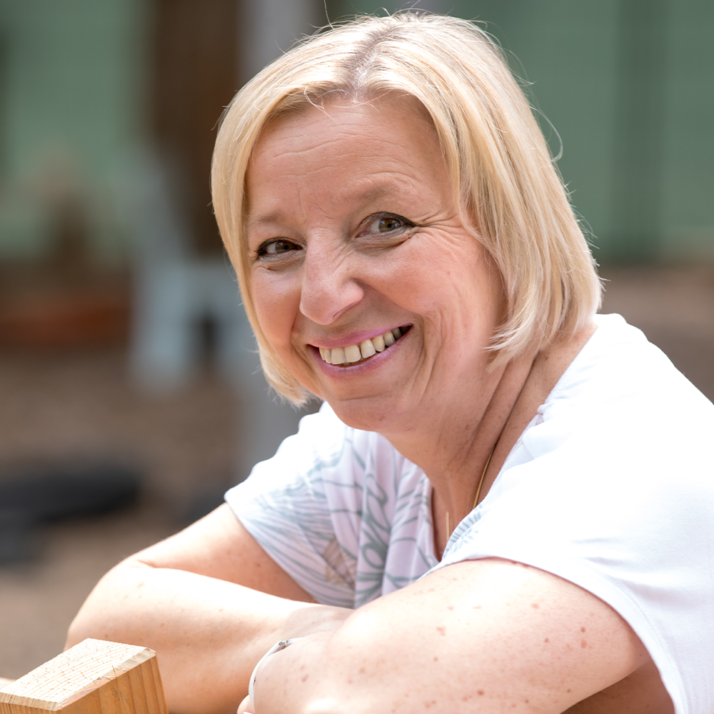 Eine Frau mit blonden Haaren lächelt in die Kamera