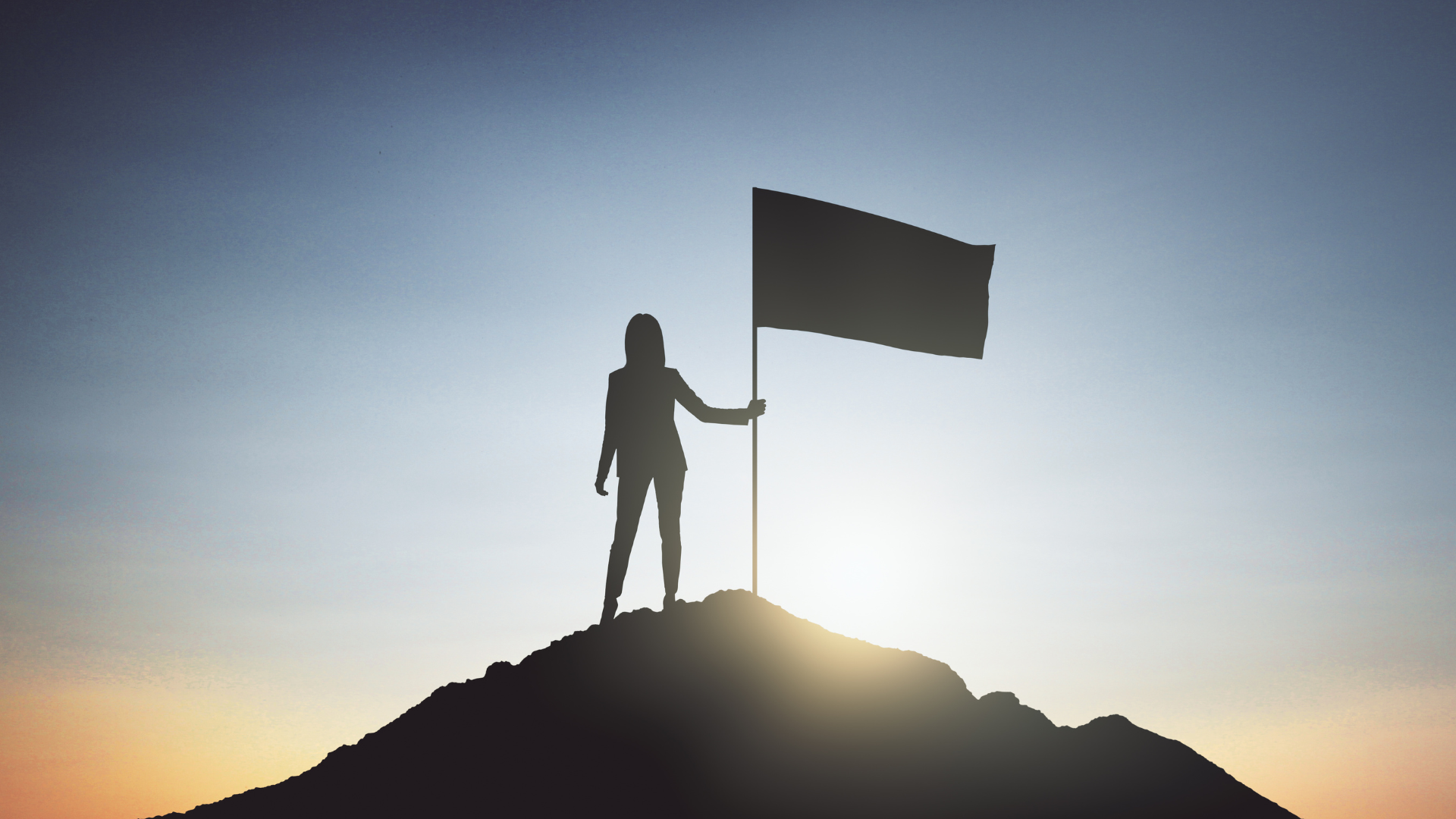 An image representing the spirit of achievement and success in the web design section of Rawlings Media's website. It features the silhouette of a woman standing triumphantly on the top of a mountain, holding a flag. The image symbolizes the ability of Rawlings Media to transform your ambitions into a captivating online presence and bring your ideas to new heights.