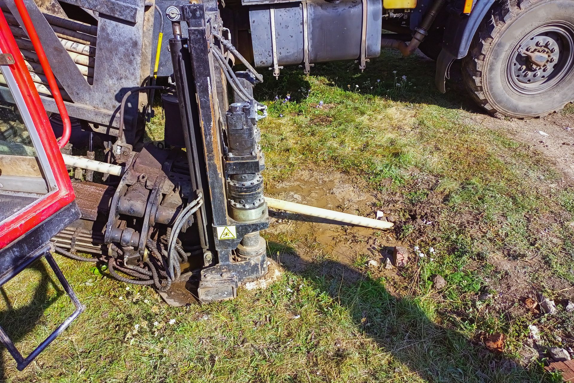 Directional drilling rig set up on grass with drill pipe extending underground. Directional drilling rig set up on grass with drill pipe extending underground.