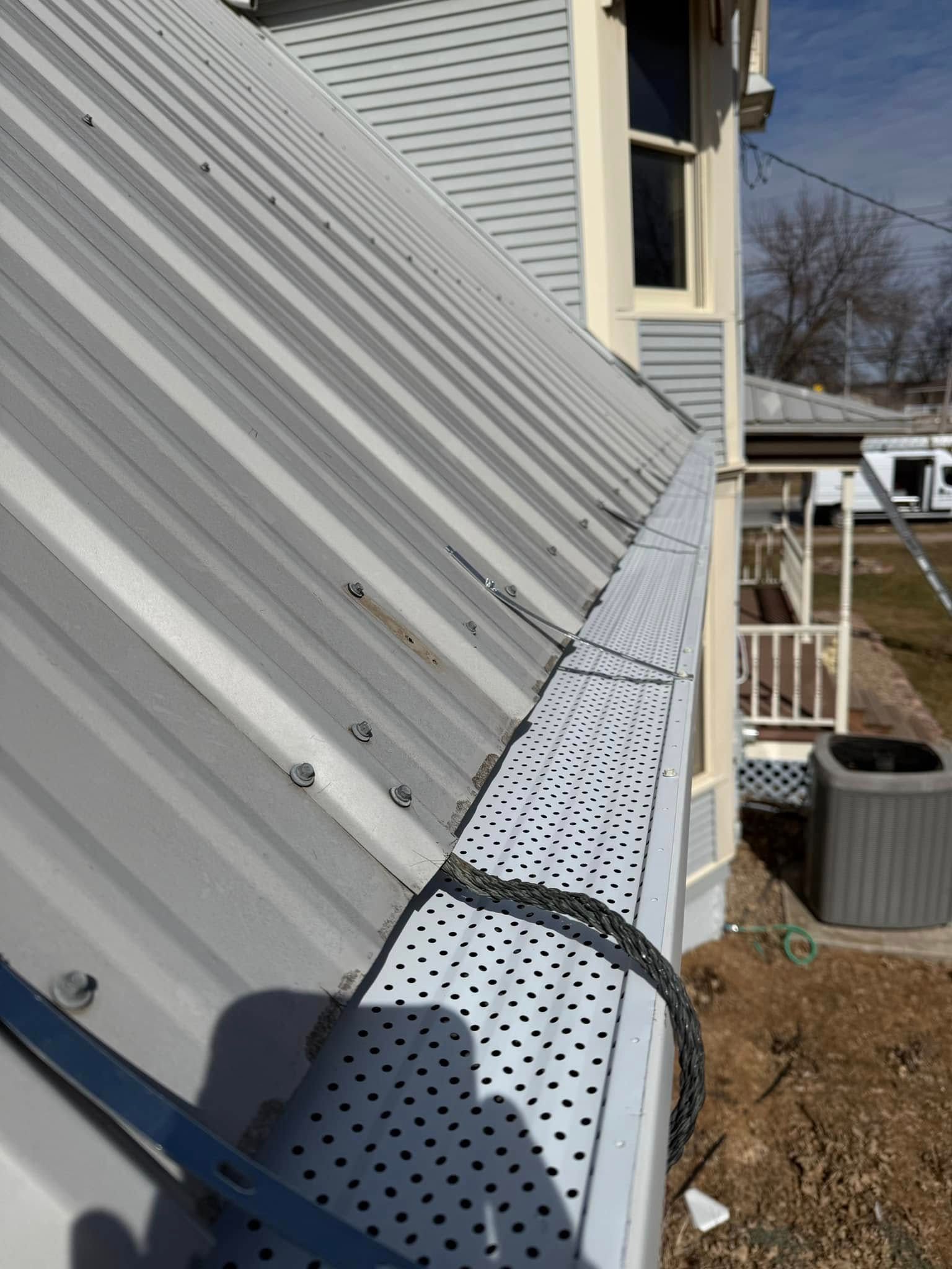 Metal roof with gutter guard; side of a light-colored house.