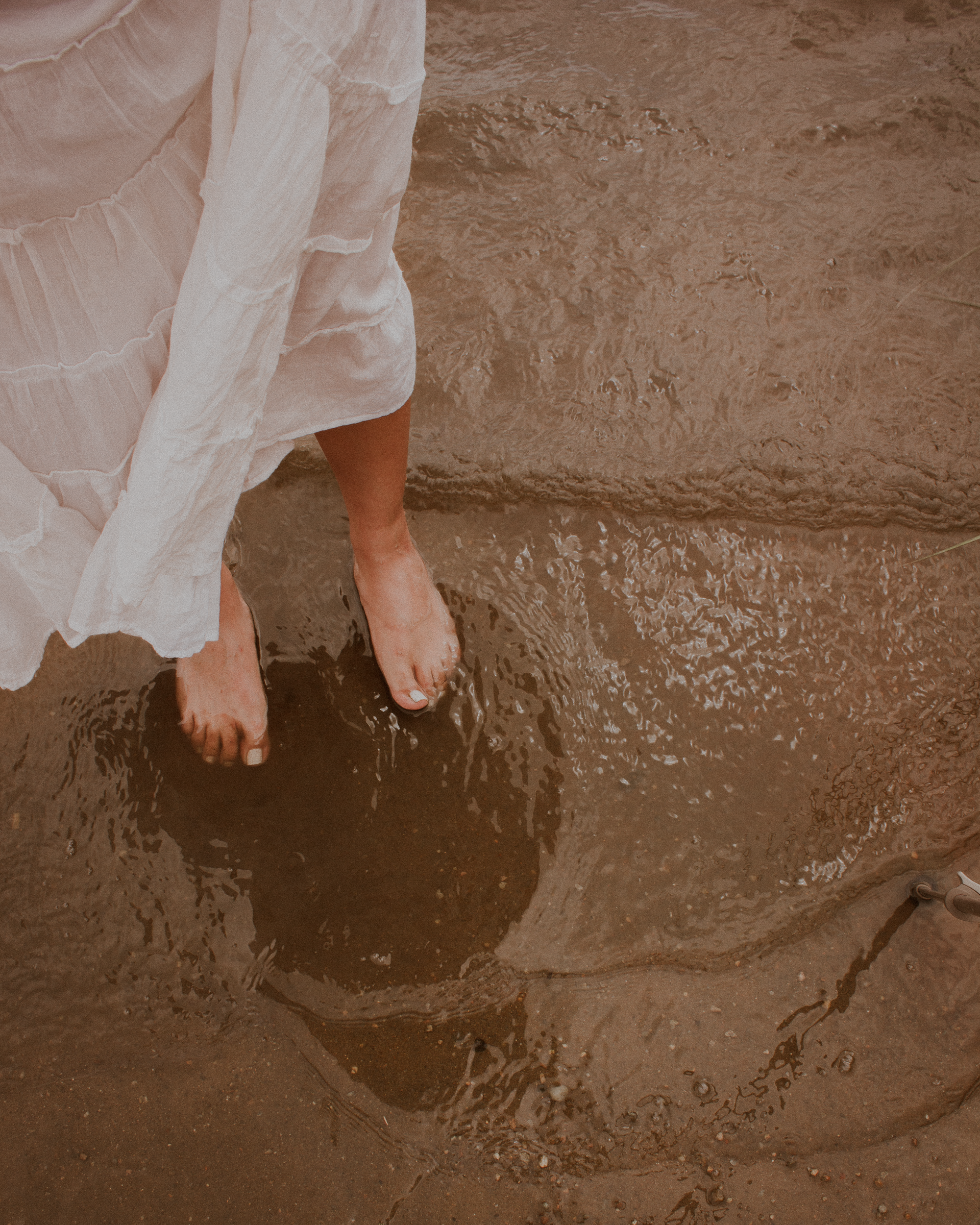 A woman in a white dress is standing in the water.