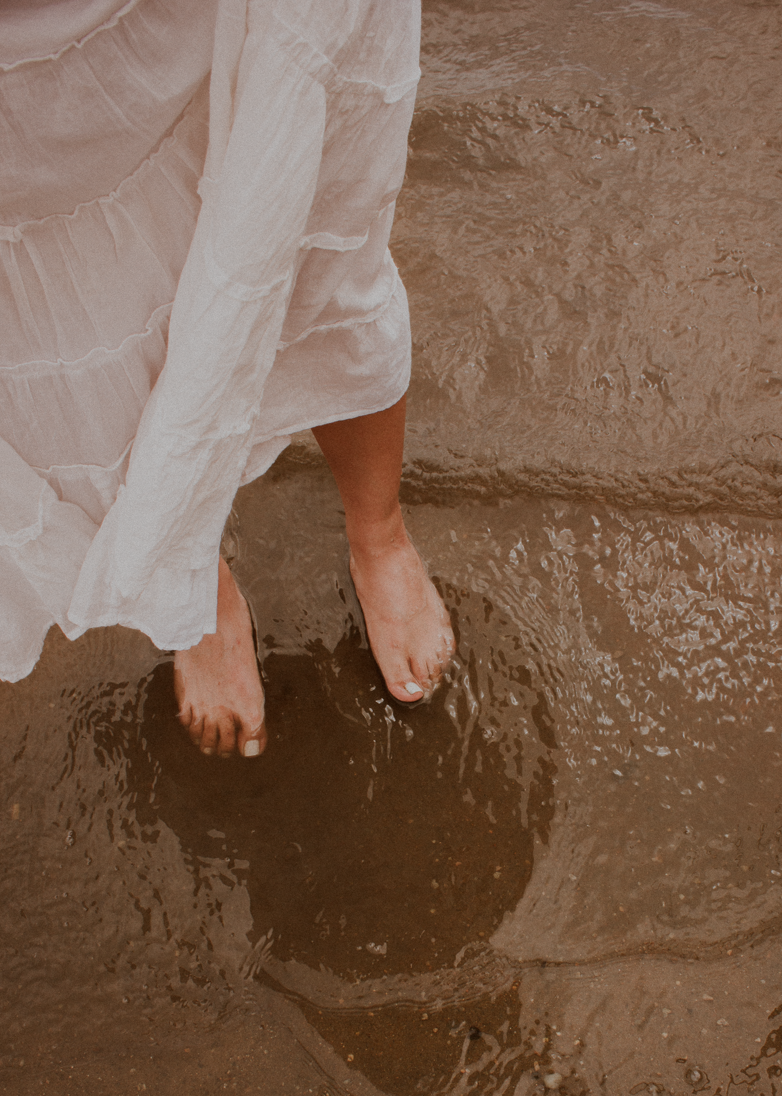 A woman in a white dress is standing in the water.