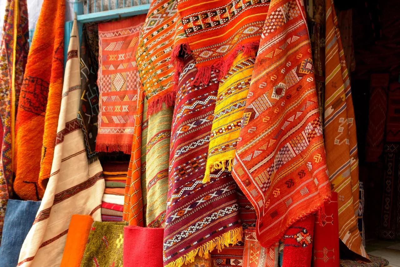 A bunch of colorful blankets are hanging on a rack.
