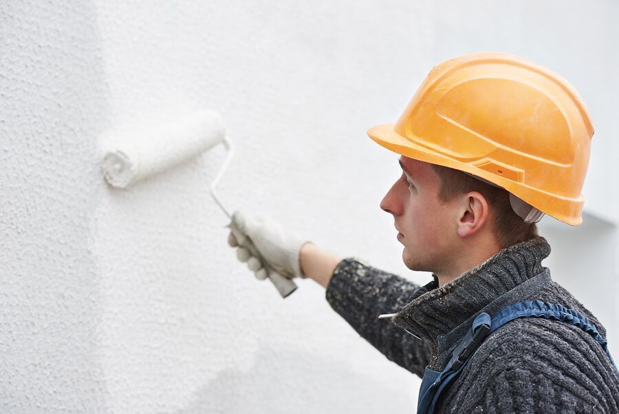 a man wearing a hard hat painting a wall