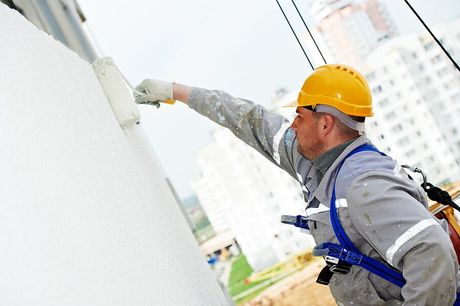 a man in a hard hat and safety gear painting a wall