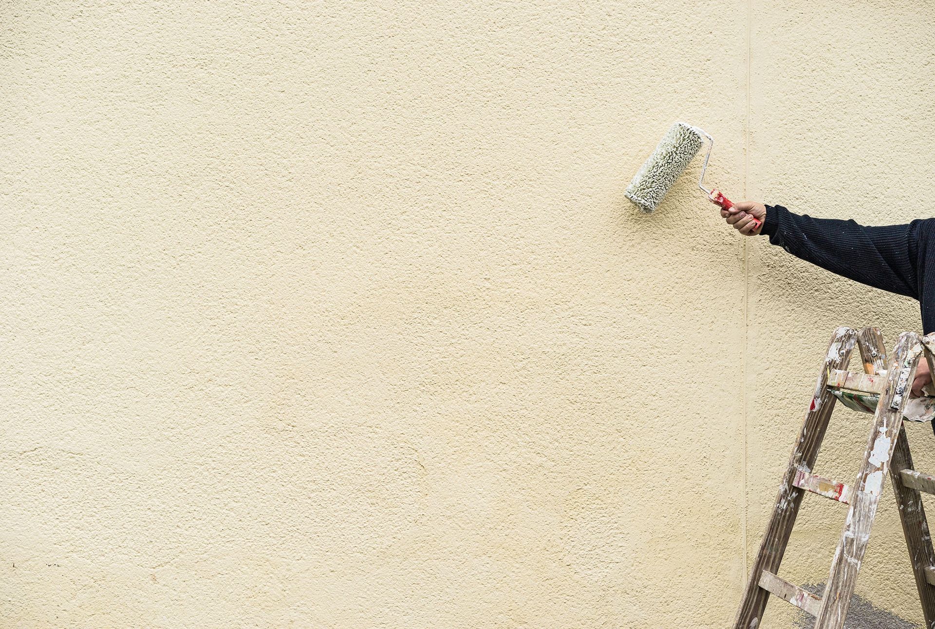 a man painting a wall with a paint roller