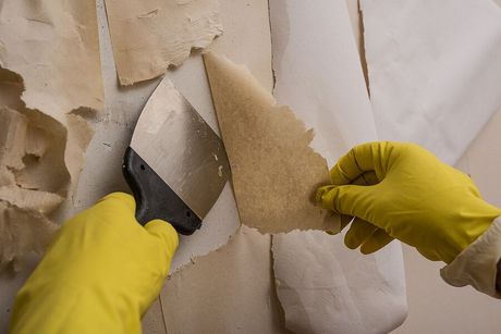 a person in yellow gloves and yellow gloves cutting a piece of paper