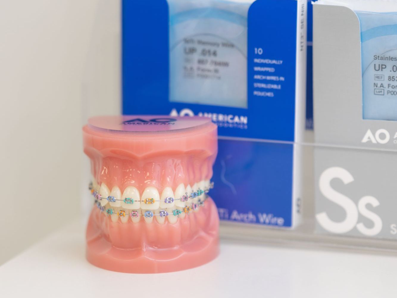 a box of american arch wire sits next to a model of teeth