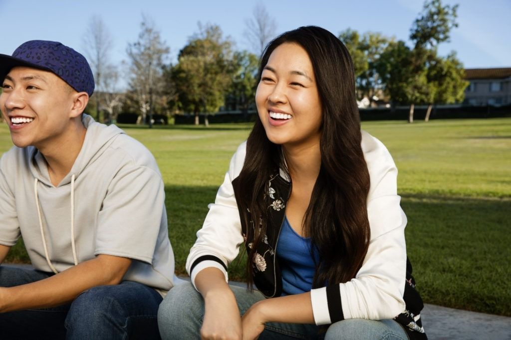 a man and a woman are sitting in the grass and smiling