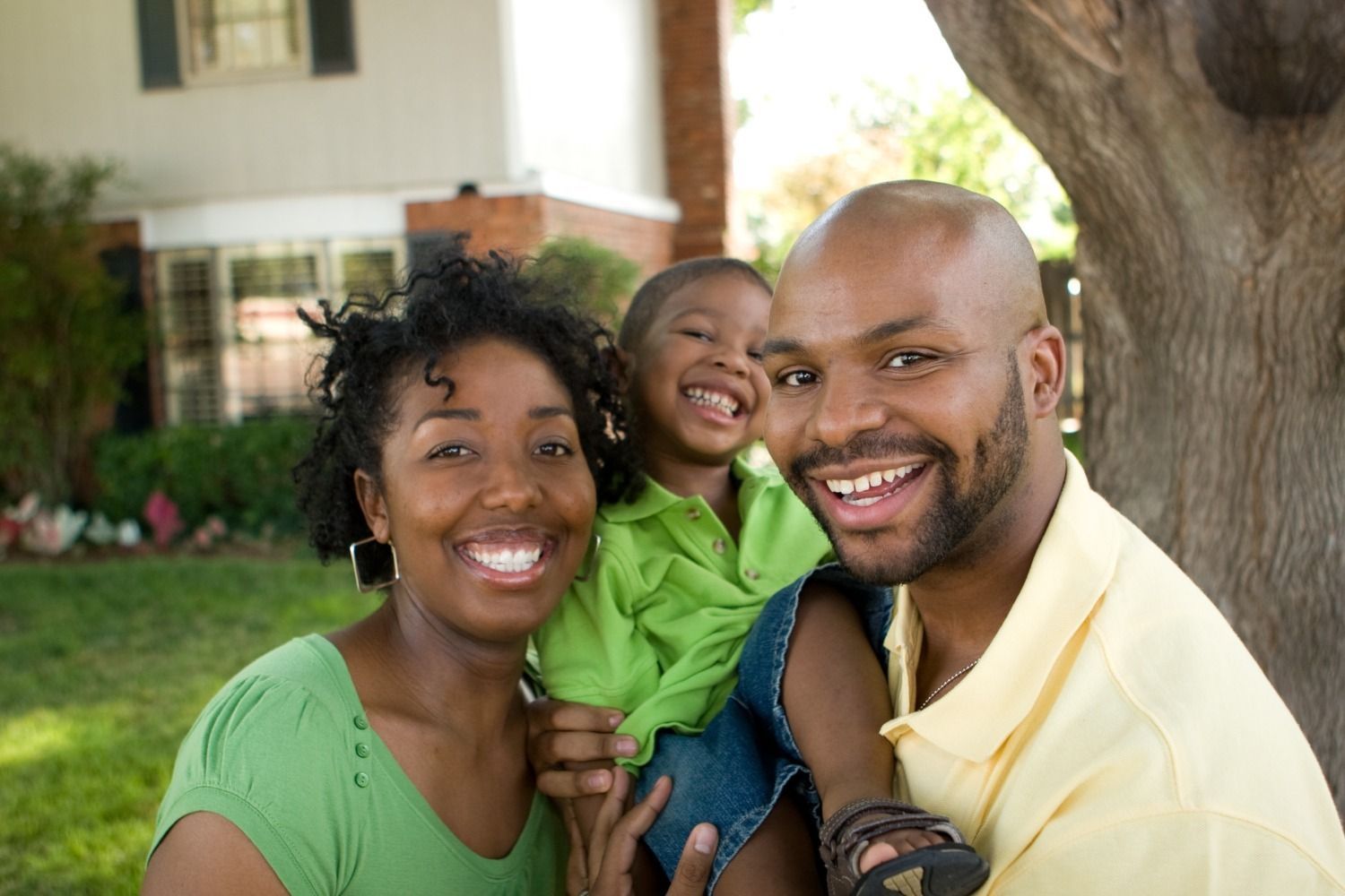 a man in a yellow shirt is holding a child in a green shirt