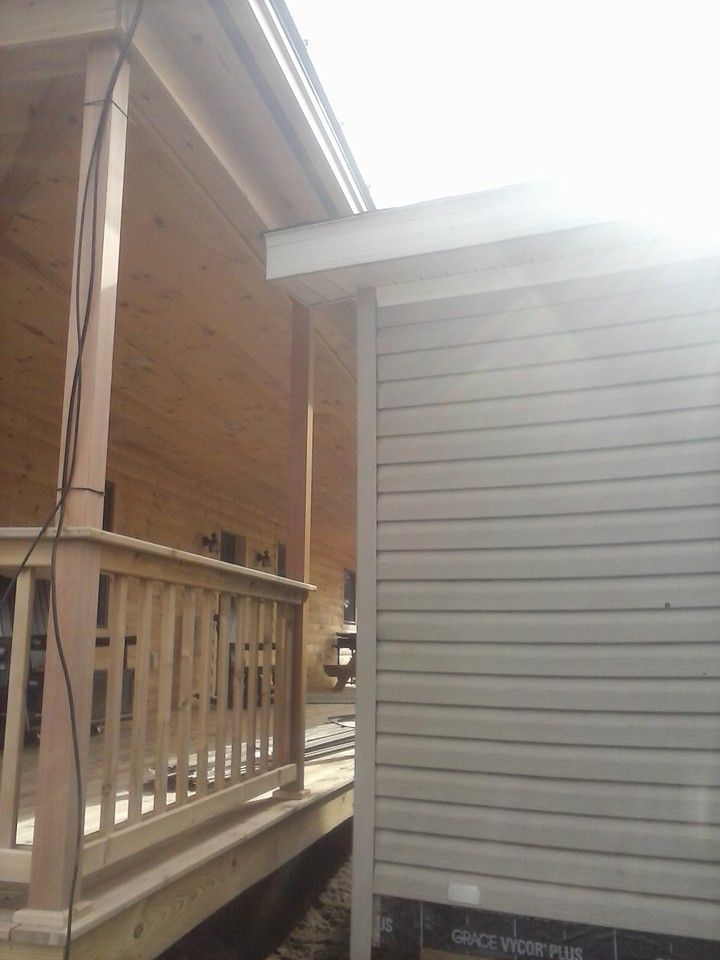 Wooden porch and tan siding on adjacent structure. Sunlit exterior view.