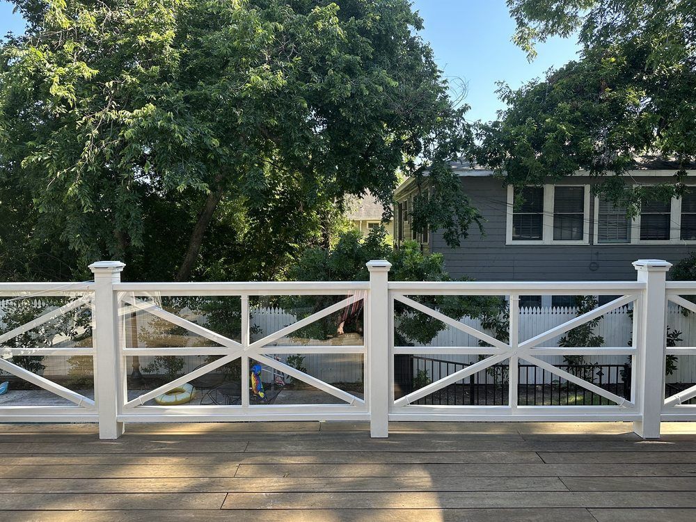 White deck railing with lattice design, overlooking a backyard with a house and trees.