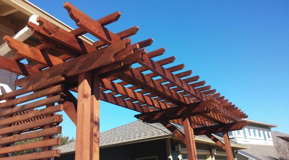 Wooden pergola with horizontal slats against a clear blue sky.