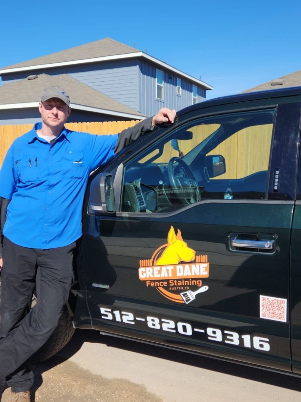 Man in blue shirt leans on a truck with 
