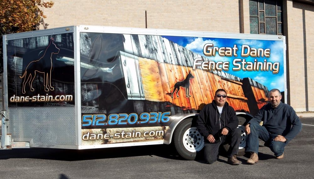 Two men kneel by a trailer advertising 