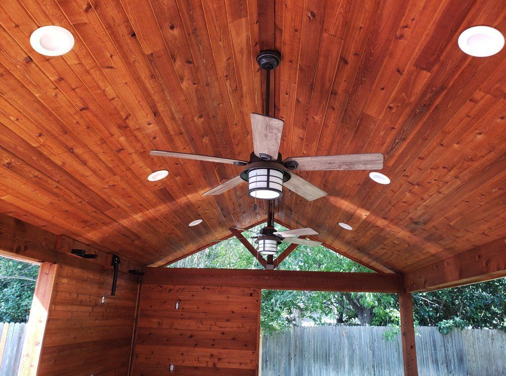 Wooden outdoor canopy with a ceiling fan, recessed lights, and wood paneling.