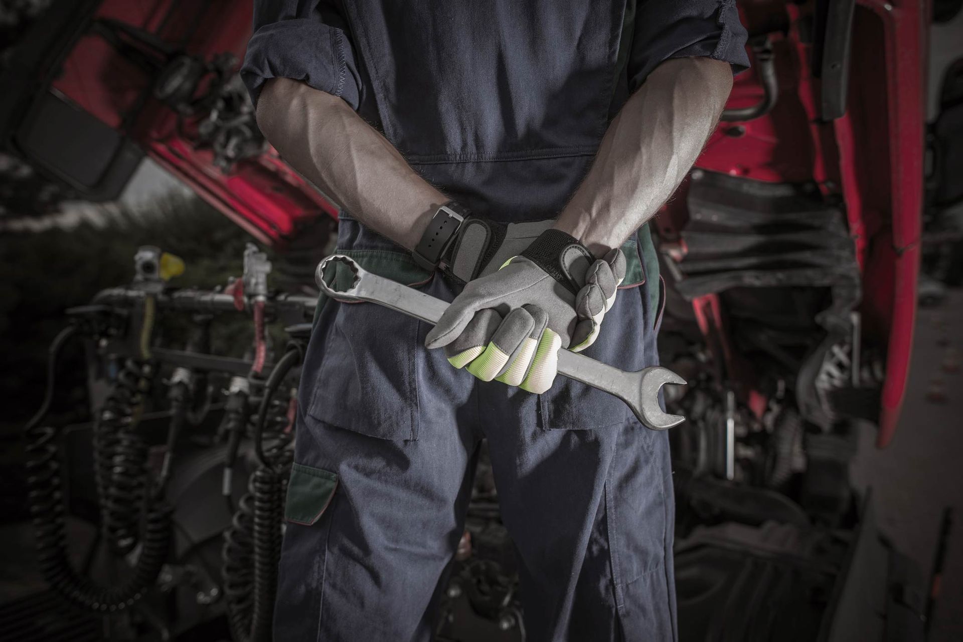 Man In Overalls Is Holding A Wrench In A Garage — Hartford, CT — Super Spring & Brake Co., Inc.
