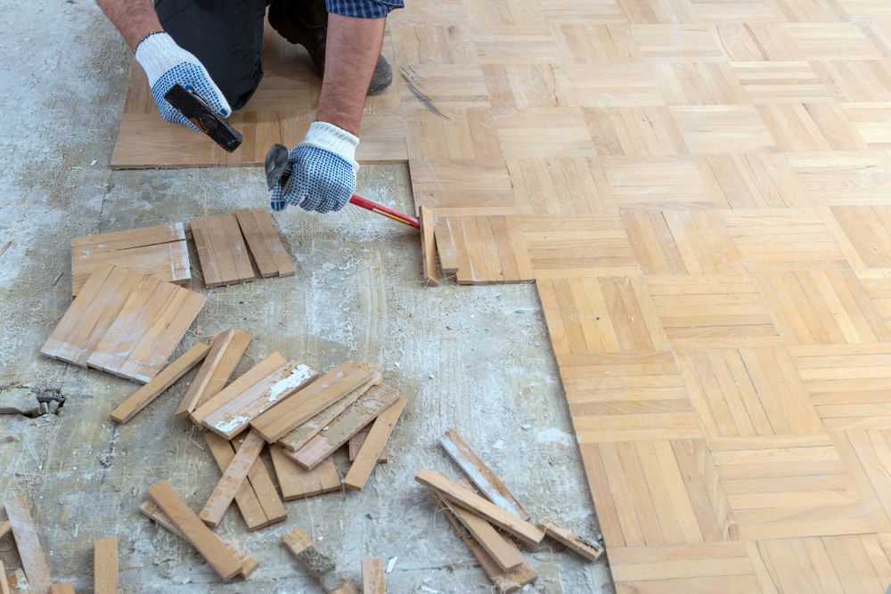 Person Installing Wood Parquet Flooring; Using Tools on Floor — Rowal Constructions in Newcastle, NSW