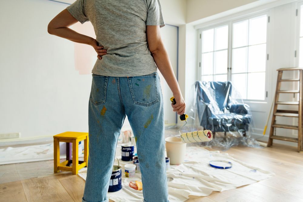 Person in Paint-splattered Jeans Holding a Paint Roller — Rowal Constructions in Merewether, NSW