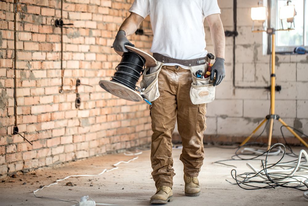 Electrician in a Construction Site Holding a Spool of Black Wire — Rowal Constructions in Wallsend, NSW