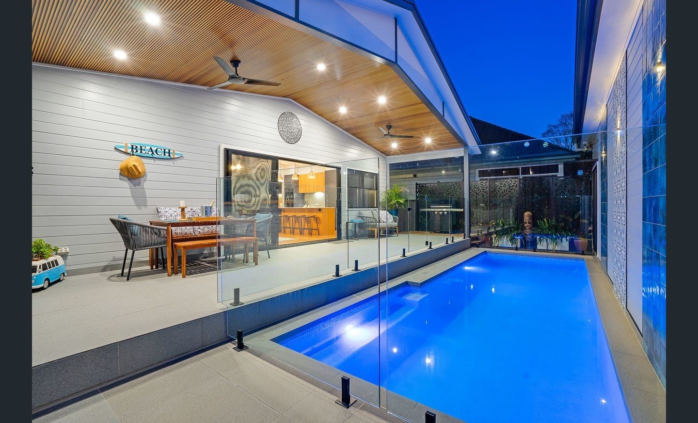 Pool area with patio seating and a rectangular pool, at dusk.