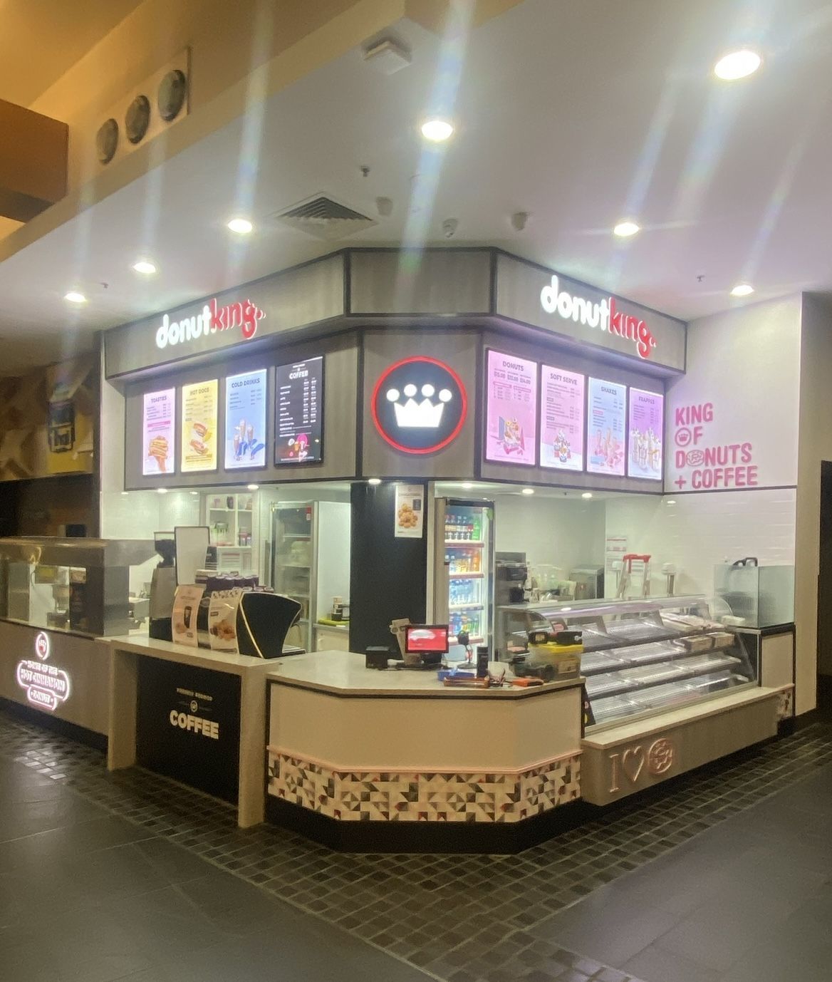 Donut King shop. Interior view. Signage with donuts & coffee. Counter with staff. Storefront in a mall.