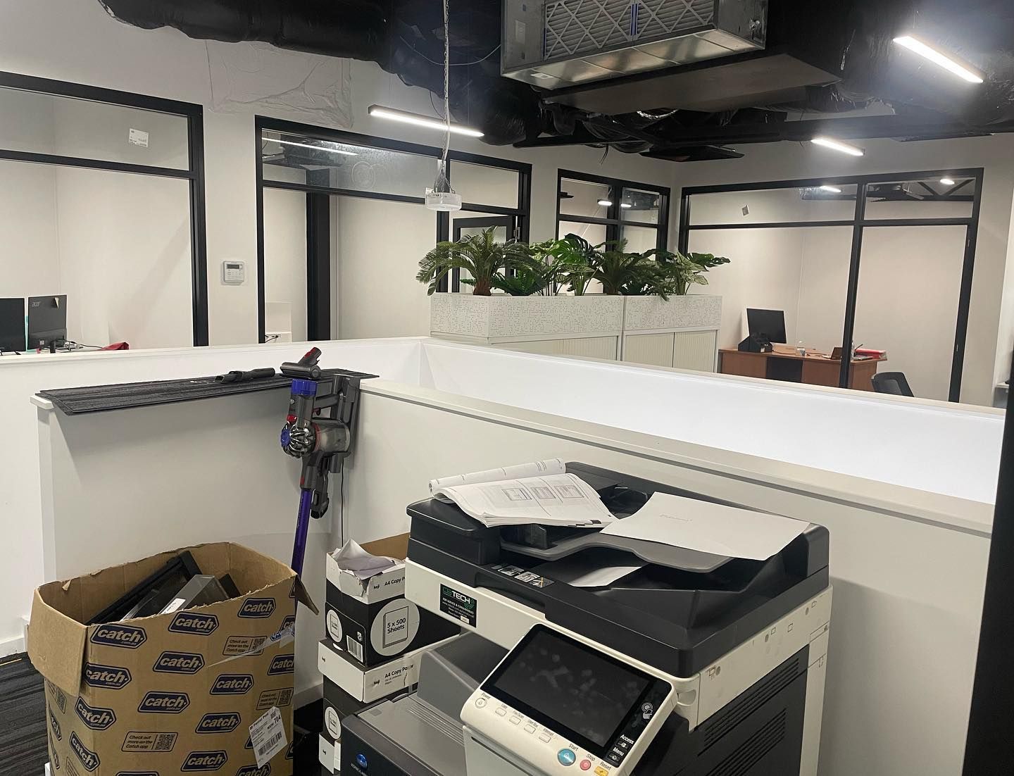 Office Interior With a Printer, Vacuum, and Plants on a White Partition — Rowal Constructions in Charlestown, NSW