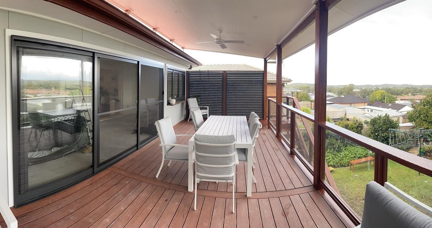 A wooden deck with a table and chairs, overlooking a cityscape.