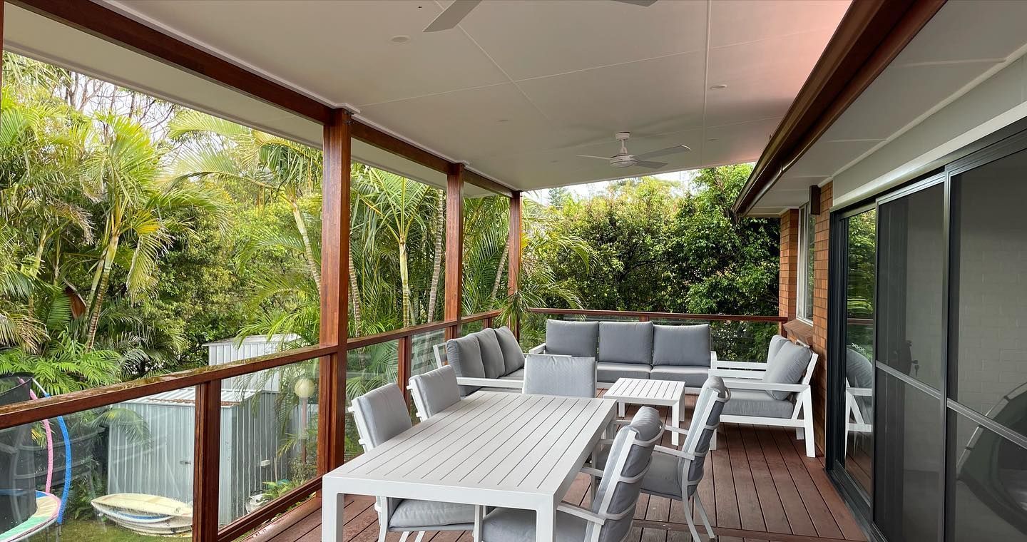 Covered deck with outdoor furniture, overlooking lush greenery.