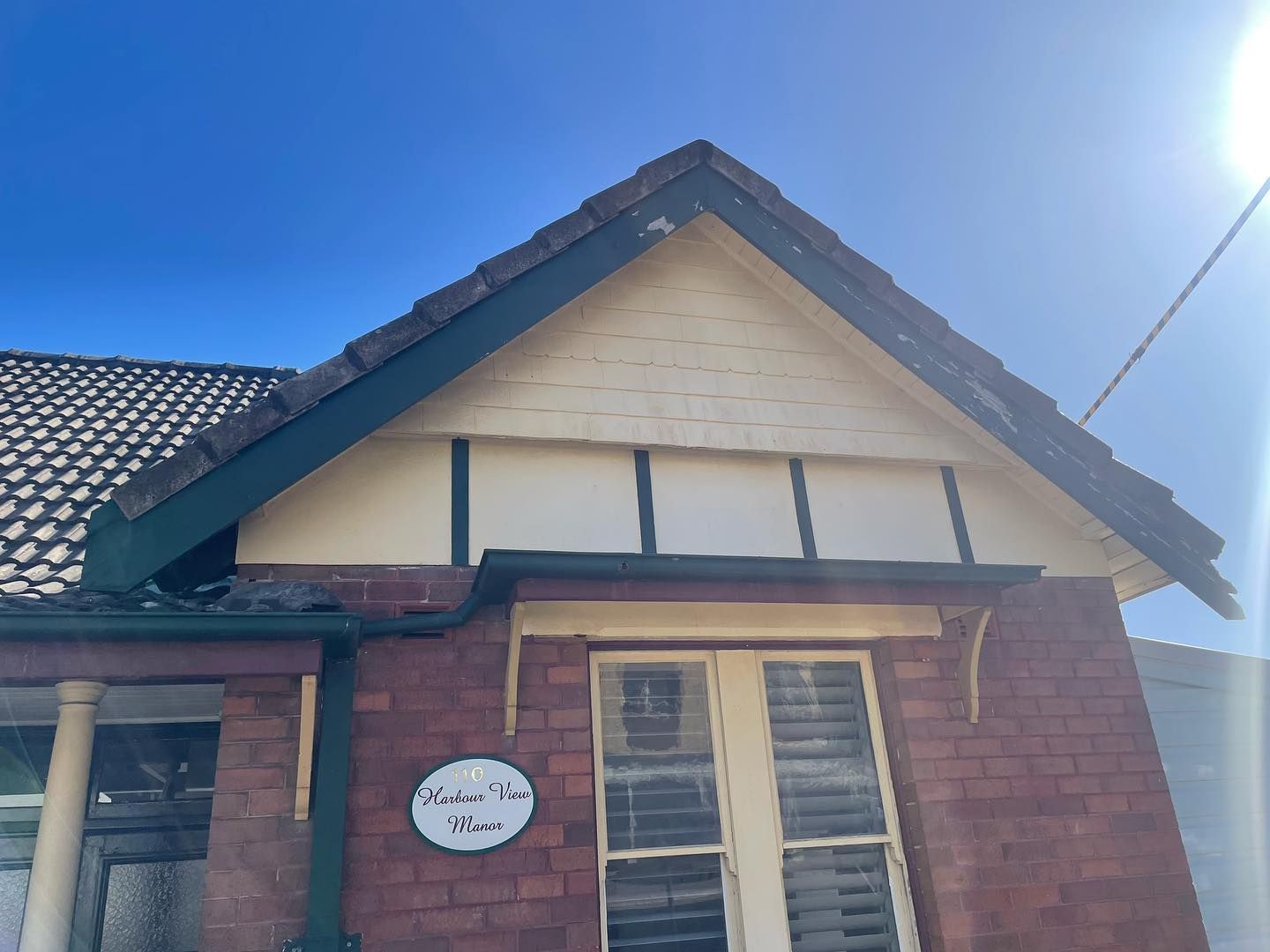 Brick Building With Gabled Roof, Tan Siding, Green Trim, and Sign Indian Tree House — Rowal Constructions in Wallsend, NSW