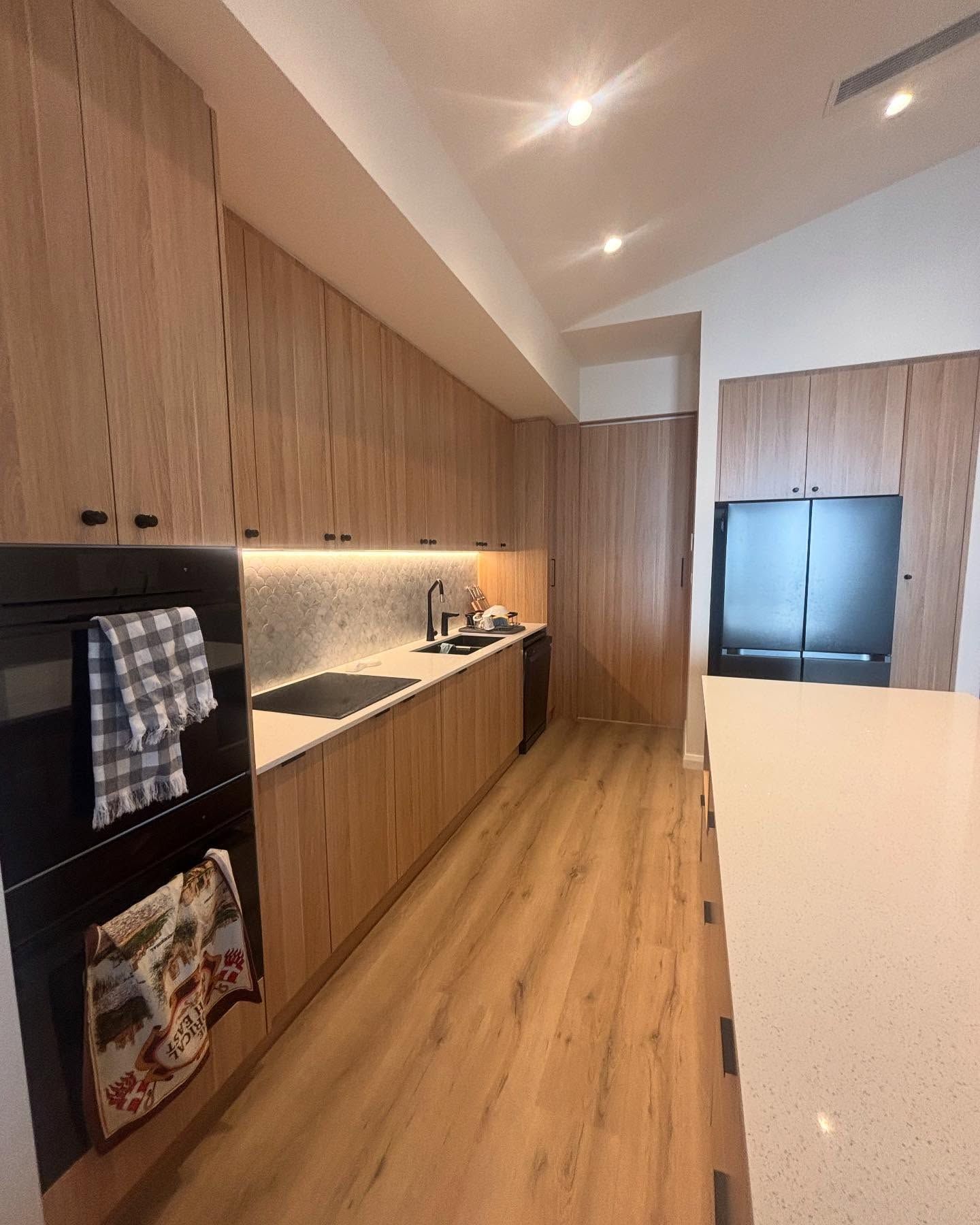 Modern Kitchen With Light Wood Cabinets, Black Appliances, and Quartz Countertops — Rowal Constructions in New Lambton, NSW