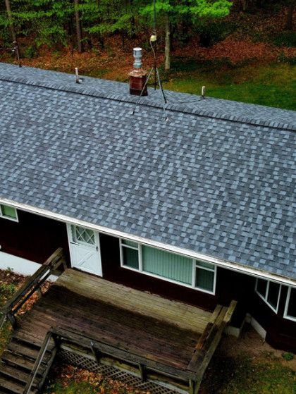An aerial view of a dark-roofed house with a deck, seen from above.