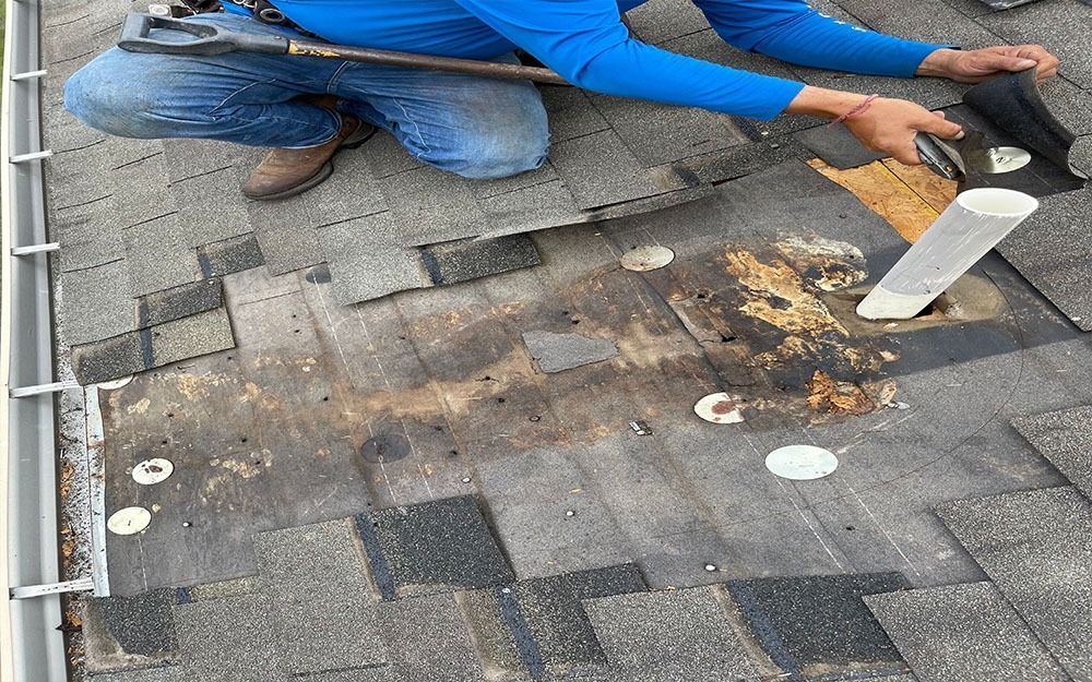 A man is kneeling down on a roof holding a wrench in San Antonio.