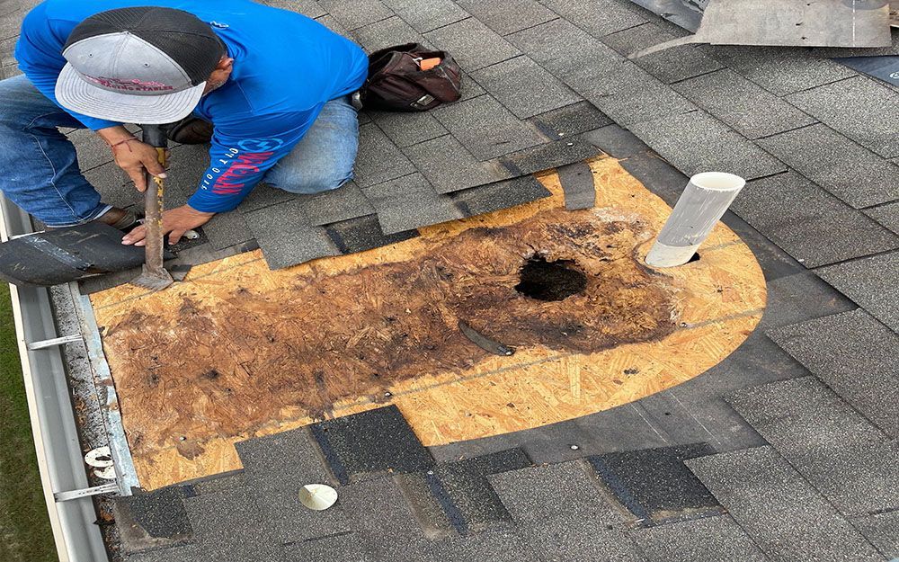 A man is working on a roof with a hammer in San Antonio.