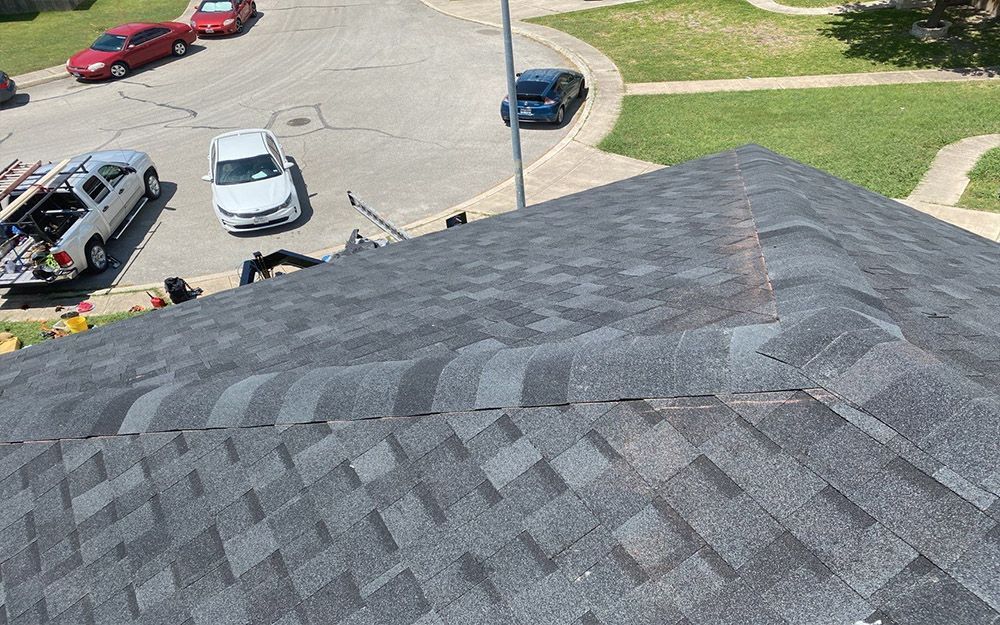 A car is parked on the ground with the roof of a building in San Antonio, TX.